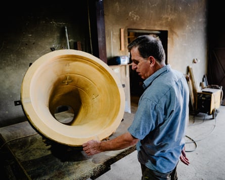 A man checking a large mould of a bell inside a workshop.