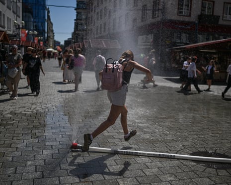 People refresh themselves by a city water curtain due to high temperatures in Wrocław, Poland.