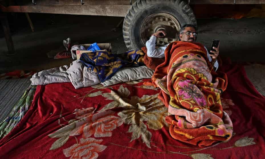 The protesting farmer checks his mobile phone while resting on a blocked highway
