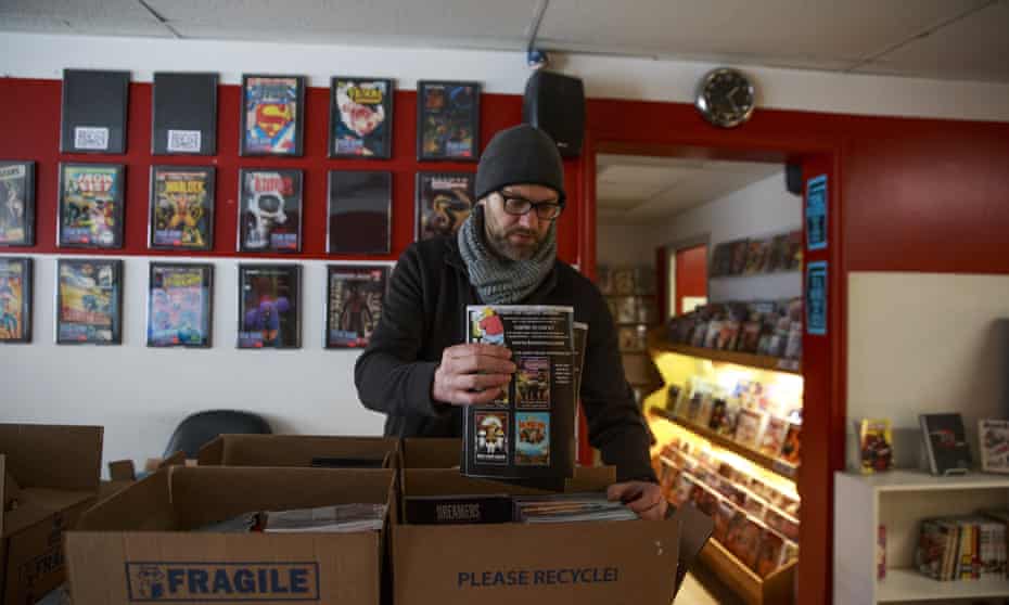 Matt Traughber, an owner of the Vintage Phoenix comic bookstop in Indiana, packs comics to distribute to subscribers a day early, on 24 March.