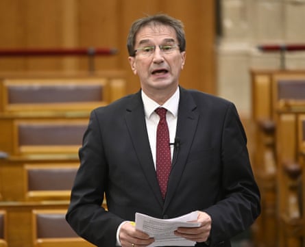 Fidesz MP Pál Völner in a suit and glasses speaks in a court while holding papers
