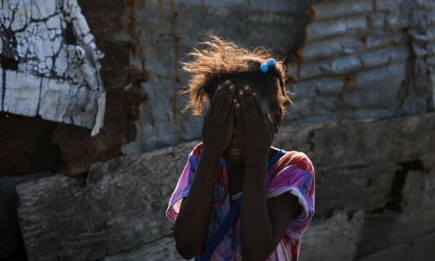 A girl wipes her face while standing in a landfill near her house in Port-au-Prince, Haiti.