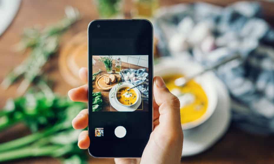 Woman taking photo of pumpkin soup with smartphone