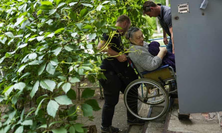A woman is carried from her home during the evacuation in Bakhmut, on 27 May.