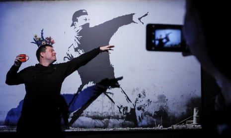 A man poses for a picture with a Banksy art work at the exhibition in Moscow