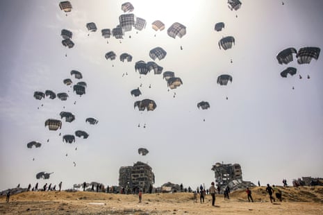 People rush to gather landing humanitarian aid packages being dropped over the northern Gaza Strip on 23 April.