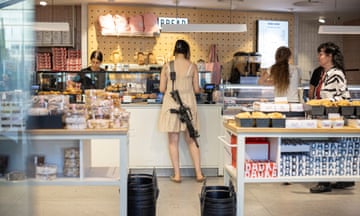 A woman with a rifle shops in a bakery in Tel Aviv.