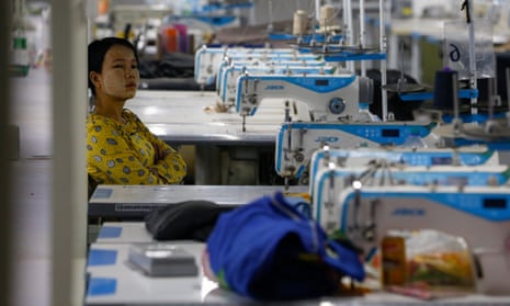A woman sits near sewing machines as workers occupy a recently closed garment factory in Myanmar to demand their salaries.