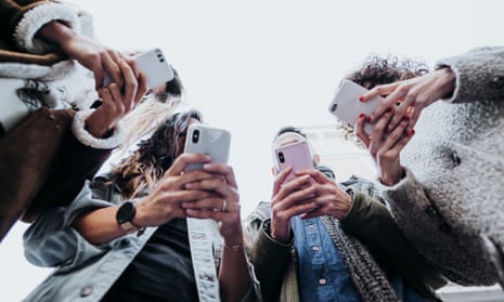 A group of people, faces obscured, looking down at their smartphones.