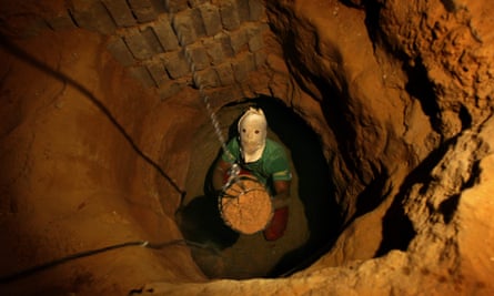 A Palestinian man, wearing a mask to conceal his identity, removes sand in a bucket while digging a tunnel in Gaza in 2007.