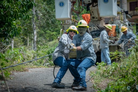 Jose Luis Gonzalez and Jose Ralat from the Puerto Rico Electric Power Authority pull a fallen line while restoring power to a single family home.