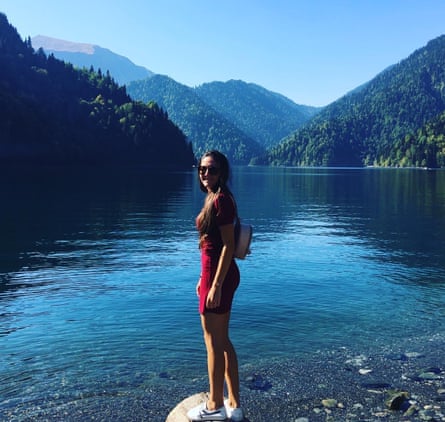 Margarita Reutt standing on a stone with a view of a river and mountains