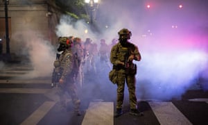 Federal agents shoot teargas and pepper balls at protesters near the federal courthouse in Portland, Oregon, on 23 July.