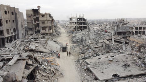 A drone view shows Palestinian people in Gaza City walking past rubble after the withdrawal of the Israeli forces from the area.