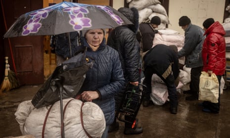 A woman stands with an umbrella after receiving blankets and aid