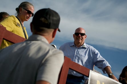 A middle-aged bald man in sunglasses smiles at supporters.