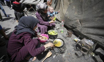 People cook on makeshift stoves in a camp in Deir al-Balah, Gaza