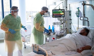 Senior doctor Thomas Marx (L) talks to a patient infected with the novel coronavirus Covid-19 in an intensive care unit at the hospital in Freising.