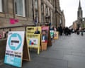 Sandwich boards with the Reform, SNP, Labour, Green and Lib Dem candidates on them, lined up outside the polling station