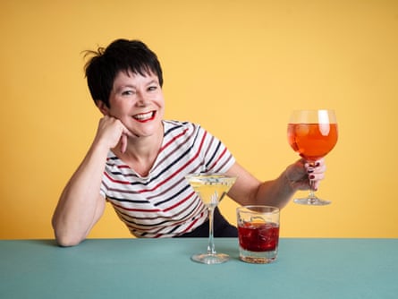 Rachel Dixon sitting at a counter with a martini drink, a negroni in a tumbler and a rosé spritz in a bowl glass.