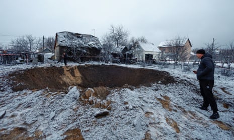 A local resident stands next to a crater at a site of a reported Russian missile strike in Kyiv.