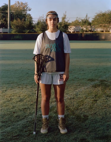 girl in sports kit with a lacrosse stick and goggles over her brow
