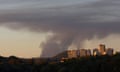 smoke rises above high-rise buildings seen at a distance.