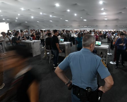 A security officer looks out on queues of people in a large room