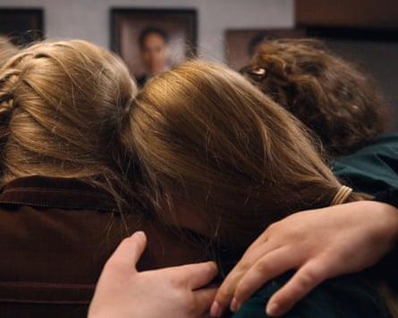 women’s heads and hands holding each other viewed from behind