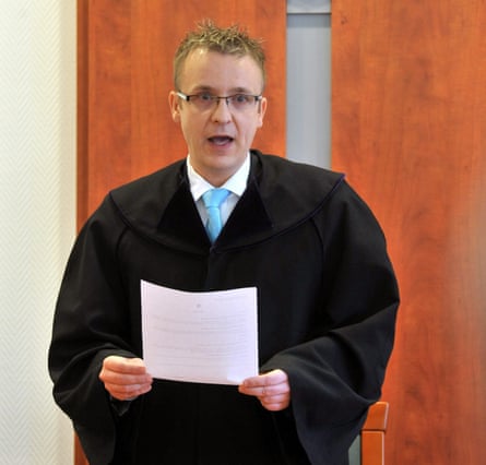 Csaba Vasvári in judge’s robes, glasses and a tie reading from a piece of paper