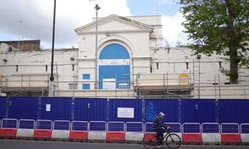 A man cycles past builders' hoardings at Pentonville prison