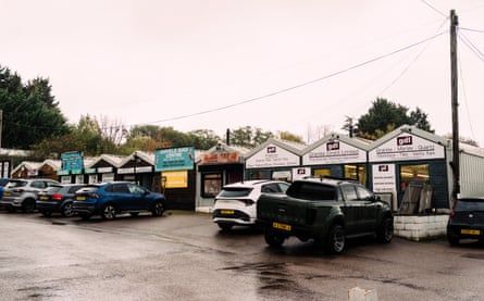 A row of small shops with cars parked in front of them.