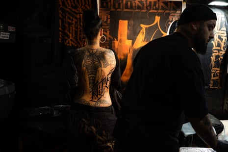 A client sits for a custom script tattoo on her back