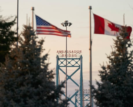 American and Canadian flags fly over bridge