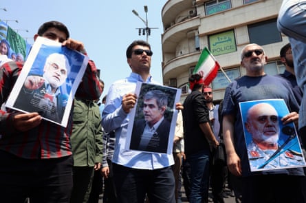People holding photographs with the flag of Iran in the background