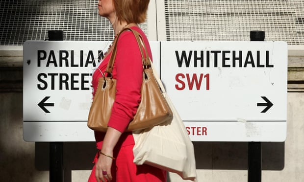 A pedestrian walking past a sign on Whitehall, London