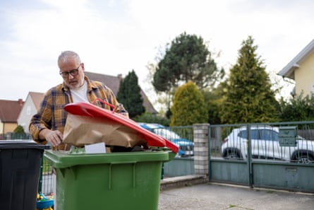 Elderly man putting paper into the waste paper box in his back yard in Lower Austria. RecyclingPeople separate waste at home for recycling, sorting garbage at home. Sustainable living concept, reusable resources, zero waste. Altpapier in Lower Austria