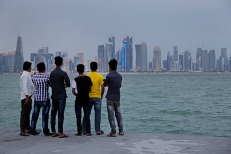 Migrant workers look across the water to the skyscrapers of West Bay in Doha on their day off.