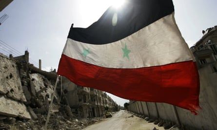 Reduced to rubble: a Syrian flag flutters outside a military barracks in the devastated Baba Amr neighbourhood.