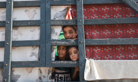 Children look out from a makeshift shelter