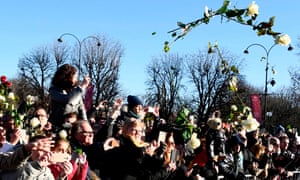 Mourners throw white roses as the hearse makes it’s way to the ceremony