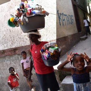 Port-au-Prince, Haiti On International Women’s Day a woman sells cleaning products near children playing, in Jalousie neighbourhood, in the commune of Petion Ville