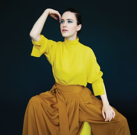 Rachel Brosnahan in a bright yellow lose-fitting top with a polo neck and orange/gold billowing trousers