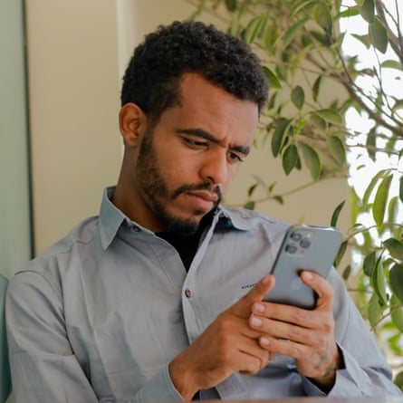 Naty Mon sits looking at a phone.