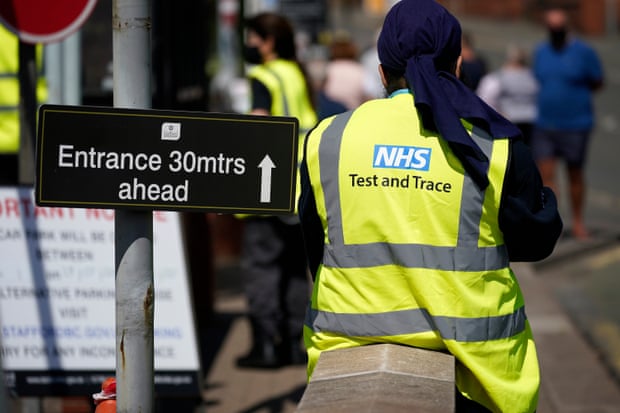 A Serco employee working on behalf of NHS Test and Trace seen from behind wearing an NHS hi-vis jacket