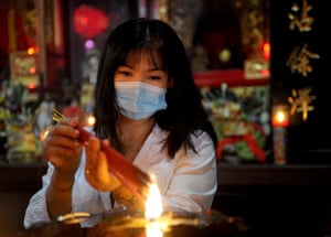A woman burns incense sticks to pray at a Chinese temple in Kuta, Bali, Indonesia