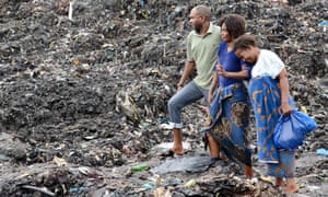 People watch rescuers searching for bodies under collapsed garbage piles in Maputo