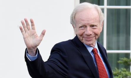 Joe Lieberman, wearing a red tie and suit, waves as he leaves the White House. 