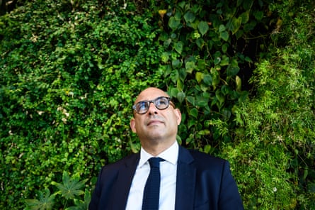 Simon Stiell looks up as he has his picture taken in front of green foliage
