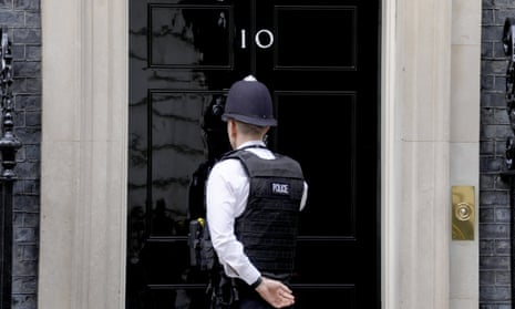 A police officer knocks on the door of 10 Downing Street in London.
